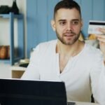 Man holding credit card while looking at laptop