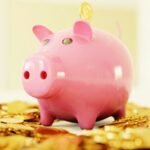 A pink piggy bank surrounded by a pile of gold coins