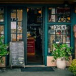 Green storefront with open signs and plants