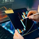 Trader analyzing stock market charts on tablet and monitor