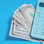 Us dollar bills and a calculator on blue background